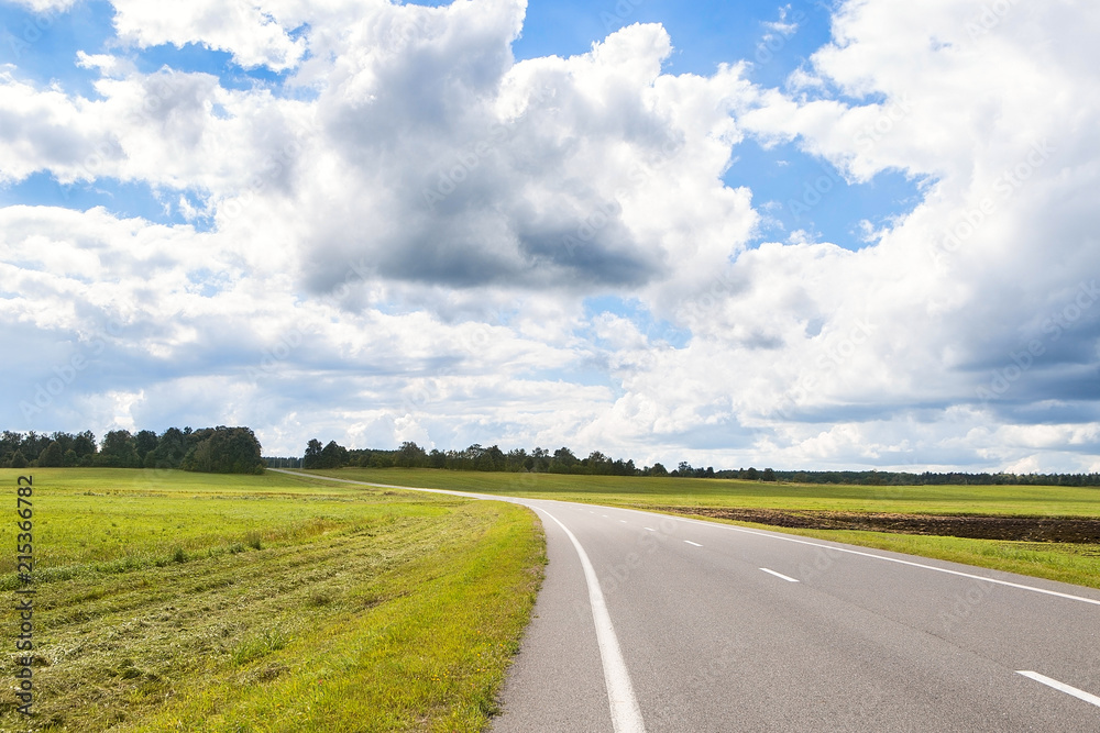 Beautiful and sunny road landscape with sky clouds and yellow fields