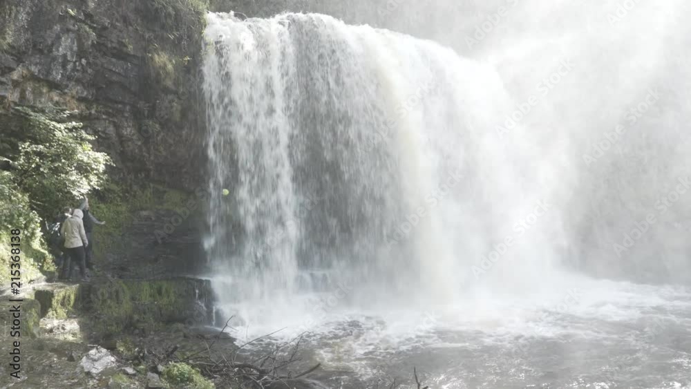 People walking behind a waterfall in Wales. People walking behind a waterfall in Wales.