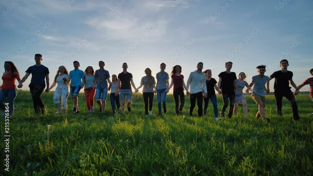 Group of friends go happily together in the grass