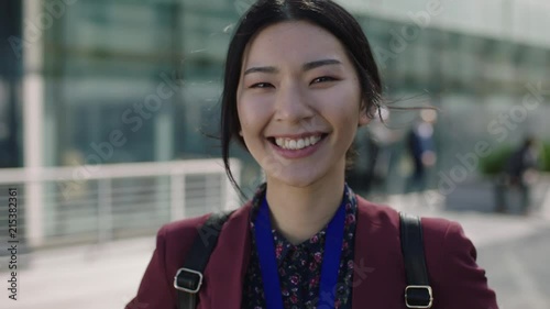 close up portrait of young asian student woman looking to camera hair blowing in wind laughing photo