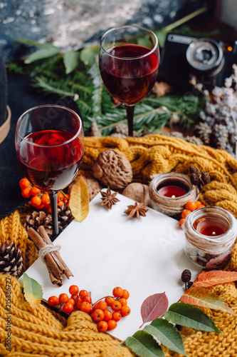  Wine in glasses ,red berries,bumps, candles and autumn branches on wooden table. Autumn or Winter concept.