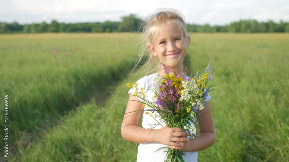 Cute little girl running in a meadow in the colors of a flowers. Carefree childhood - little child girl play on summer green meadow grass with flowers. Cute little girl running in a meadow in the colors of a flowers. Carefree childhood - little child girl play on summer green meadow grass with flowers.