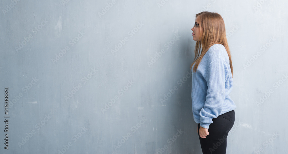 Young adult woman over grey grunge wall wearing glasses looking to side, relax profile pose with natural face with confident smile. Young adult woman over grey grunge wall wearing glasses looking to side, relax profile pose with natural face with confident smile.