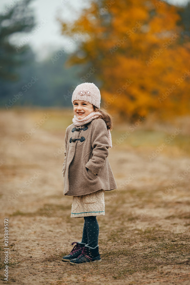 Child girl stands on forest path in autumn forest.