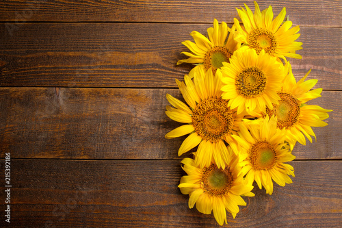 Fototapeta Naklejka Na Ścianę i Meble -  Many beautiful bright yellow sunflowers on a brown wooden background. top view with a place for inscription