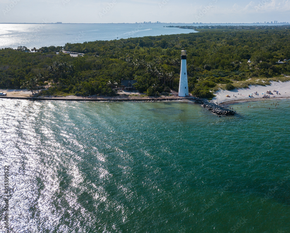 The restored Cape Florida Lighthouse on Biscayne Bay south of Miami Florida and the clear gorgeous waters and reefs as seen from above via drone