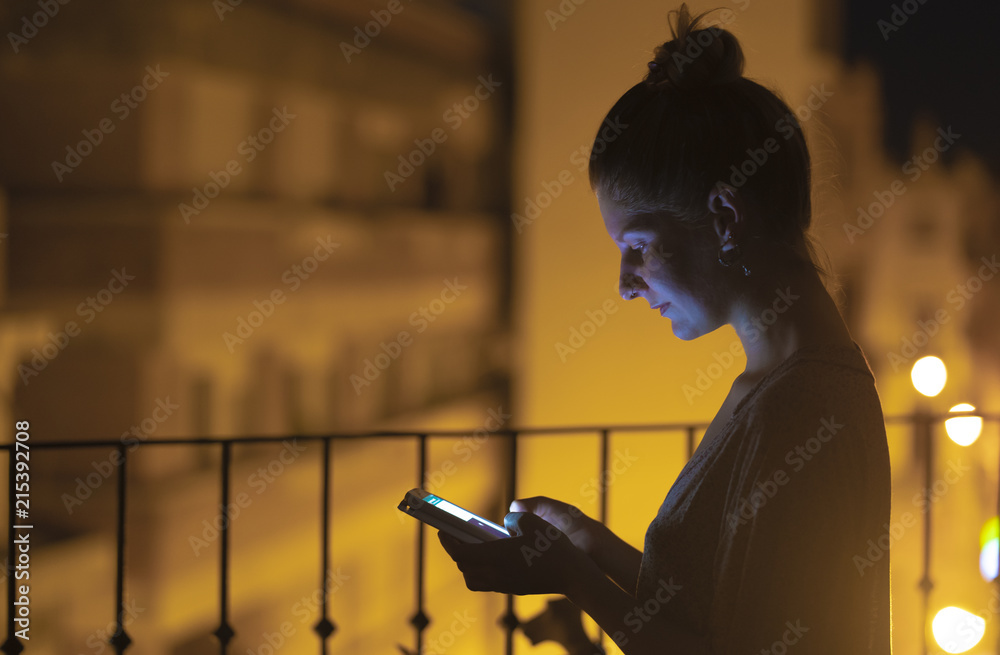 Young woman looking at her smartphone at night