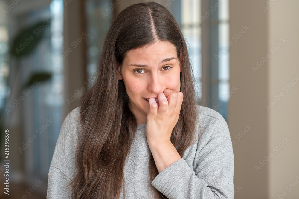 Young beautiful woman at home looking stressed and nervous with hands on mouth biting nails. Anxiety problem. Young beautiful woman at home looking stressed and nervous with hands on mouth biting nails. Anxiety problem.