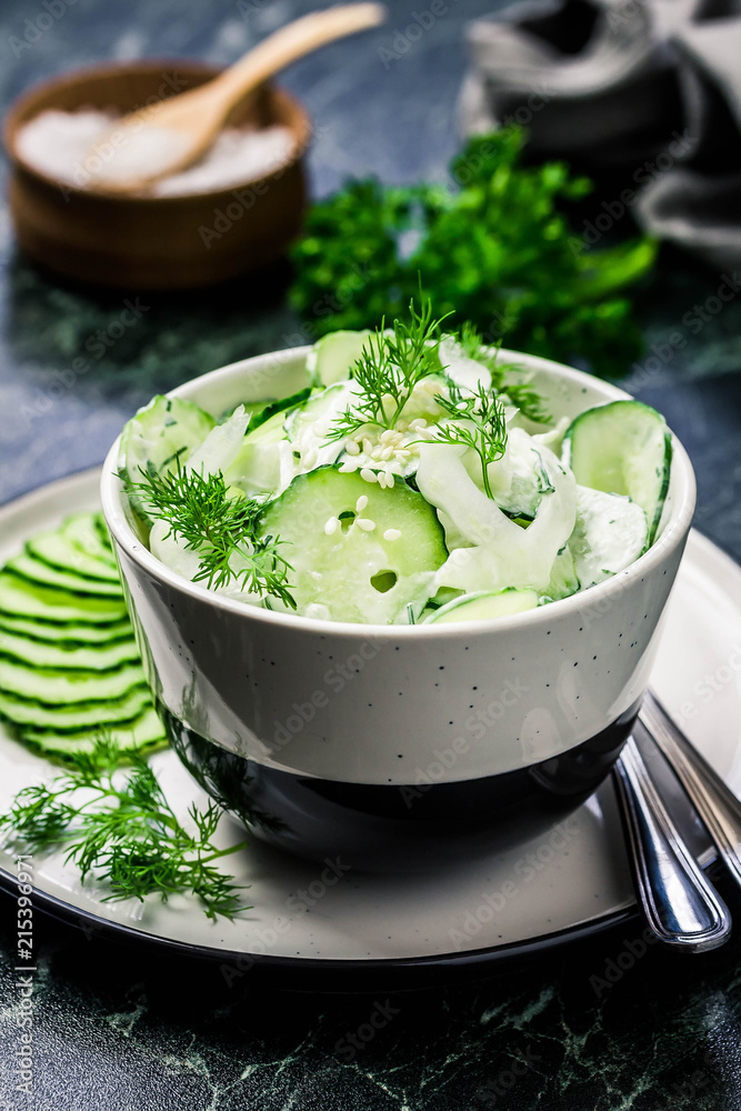 Creamy cucumber dill salad with yogurt dressing on dark marble background. Selective focus, space for text. Creamy cucumber dill salad with yogurt dressing on dark marble background. Selective focus, space for text.