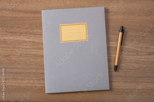 Grey school notebook or diary, old fashioned, on wooden desk, blank label, space for text, top view