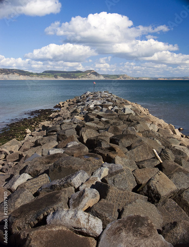 The breakwater at Lyme Regis in Dorset protecting the entrance to the marina, with vies of Seatown cliffs. photo