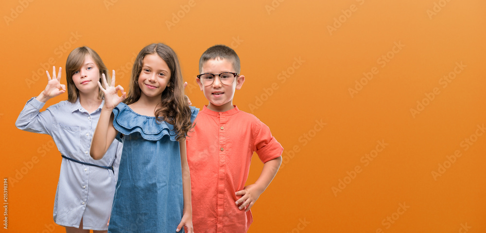 Group of boy and girls kids over orange background doing ok sign with fingers, excellent symbol