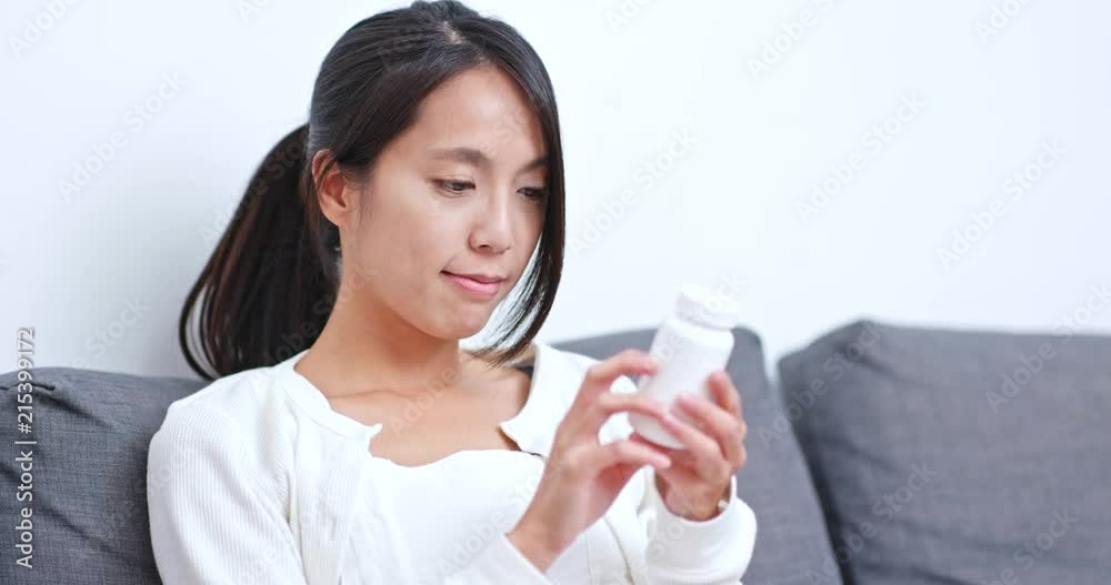Woman checking the list on pill bottle at home Woman checking the list on pill bottle at home