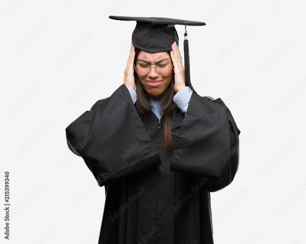 Young hispanic woman wearing graduated cap and uniform suffering from headache desperate and stressed because pain and migraine. Hands on head. Young hispanic woman wearing graduated cap and uniform suffering from headache desperate and stressed because pain and migraine. Hands on head.