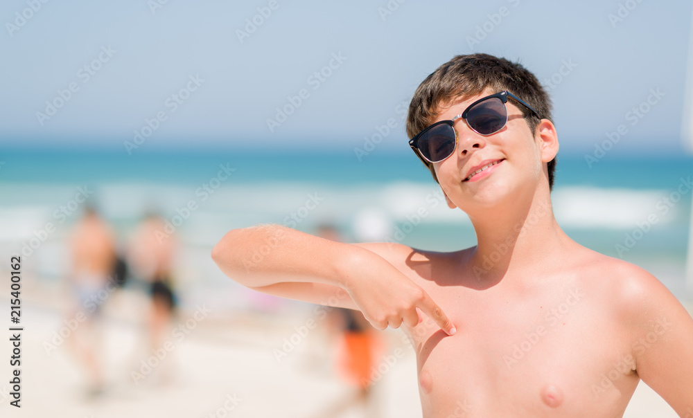 Young child on holidays by the beach with surprise face pointing finger to himself Young child on holidays by the beach with surprise face pointing finger to himself