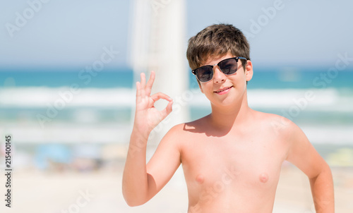 Young child on holidays by the beach doing ok sign with fingers, excellent symbol © Krakenimages.com