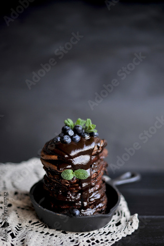 chocolate pancakes for breakfast with blueberries, dark photo. Homemade baking