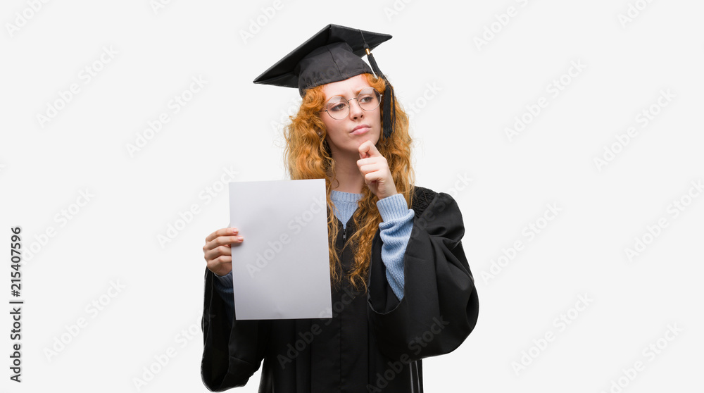 Young redhead woman wearing graduate uniform holding degree serious face thinking about question, very confused idea Young redhead woman wearing graduate uniform holding degree serious face thinking about question, very confused idea