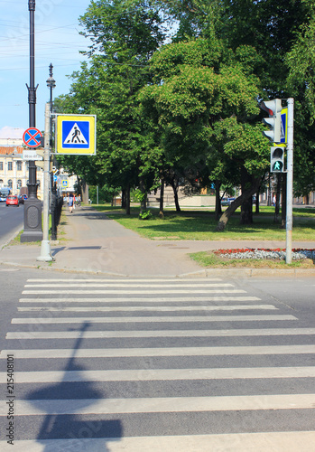 Pedestrian Crosswalk with Sign, Parallel Pattern of White Lines on Grey Asphalt Background on Summer Day. Empty Pedestrian Crossing Point at Downtown City Street on Bright Summer Sunny Day.