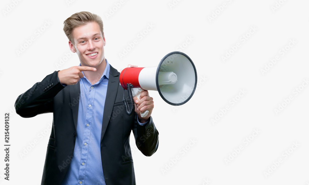 Young handsome blond man holding a megaphone very happy pointing with hand and finger Young handsome blond man holding a megaphone very happy pointing with hand and finger