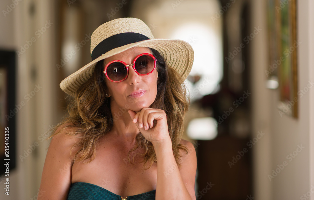 Middle age brunette woman wearing sunglasses serious face thinking about question, very confused idea