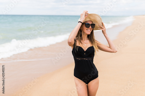 Young pretty woman in hat on the beach near sea