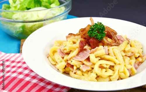 Spätzel or Spaetzel or soft egg noodle fried with ham ,cheese and Topped with fried onions and bacon.