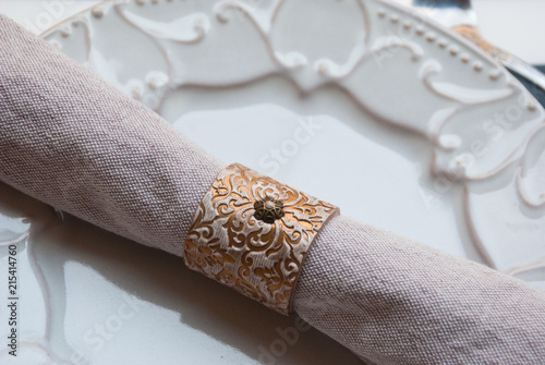 Gold vintage napkin ring on beautiful plate. Part of table for wedding preparation.