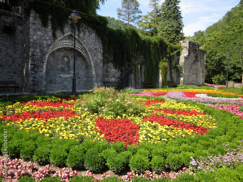 Park with flowers at summer, ornamental flowergarden next to ancient building photo