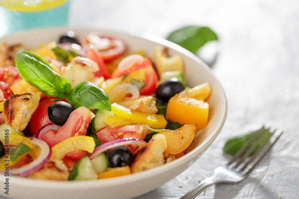 Panzanella salad with heirloom tomatoes and ciabatta in ceramic bowl on the kitchen table.