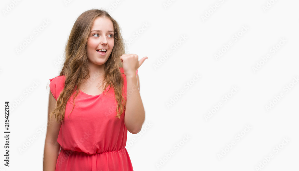 Young blonde woman wearing pink dress pointing and showing with thumb up to the side with happy face smiling Young blonde woman wearing pink dress pointing and showing with thumb up to the side with happy face smiling