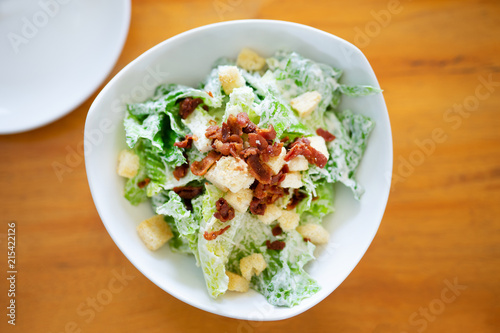 bacon topping on cesar salad on wood background