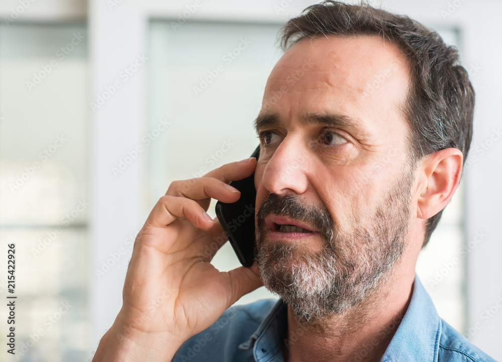 Middle age man using smartphone with a confident expression on smart face thinking serious Middle age man using smartphone with a confident expression on smart face thinking serious