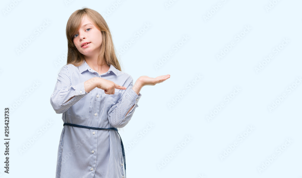 Young blonde toddler wearing blue shirt very happy pointing with hand and finger Young blonde toddler wearing blue shirt very happy pointing with hand and finger