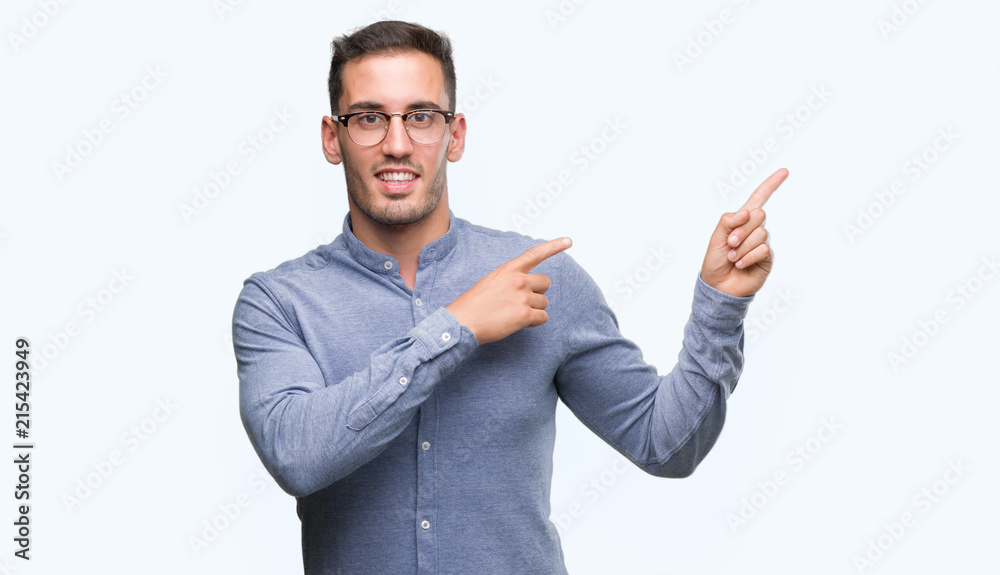 Handsome young elegant man wearing glasses smiling and looking at the camera pointing with two hands and fingers to the side. Handsome young elegant man wearing glasses smiling and looking at the camera pointing with two hands and fingers to the side.