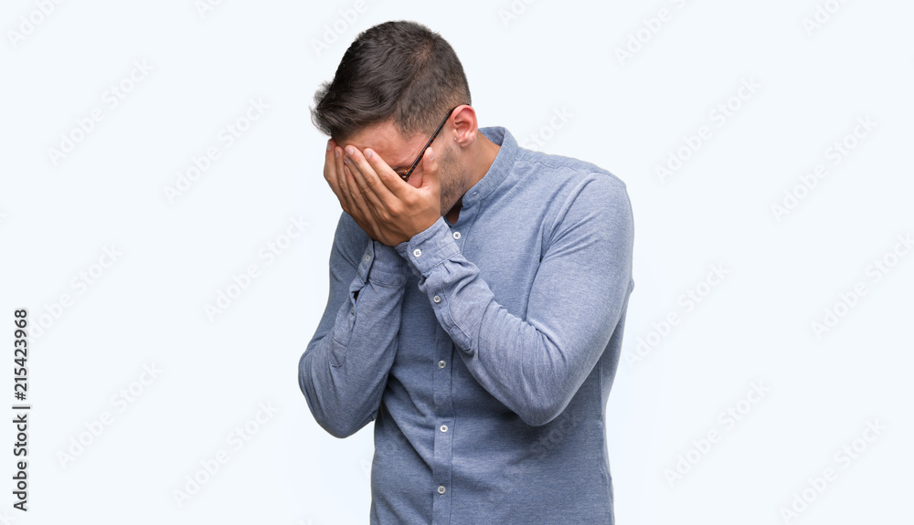 Handsome young elegant man wearing glasses with sad expression covering face with hands while crying. Depression concept. Handsome young elegant man wearing glasses with sad expression covering face with hands while crying. Depression concept.