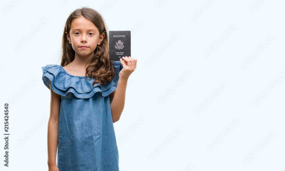 Brunette hispanic girl holding passport of United States of America with a confident expression on smart face thinking serious Brunette hispanic girl holding passport of United States of America with a confident expression on smart face thinking serious