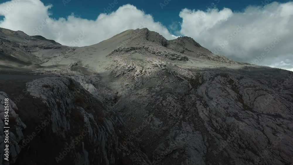 Aerial: flying by cliff towards moon like mountain Aerial: flying by cliff towards moon like mountain