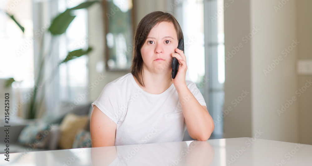 Down syndrome woman at home using smartphone with a confident expression on smart face thinking serious
