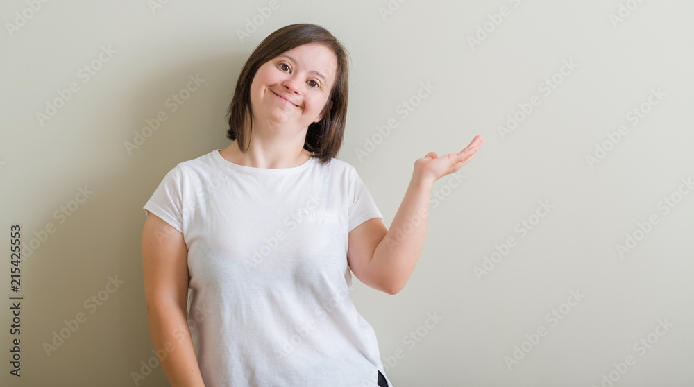 Down syndrome woman standing over wall smiling cheerful presenting and pointing with palm of hand looking at the camera. Down syndrome woman standing over wall smiling cheerful presenting and pointing with palm of hand looking at the camera.