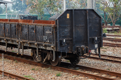 Empty old rusted cargo train at the train station in Taiwan. Railroad tracks, rusted metal, goods transportation. Rusted wheels, open top with folding doors on the outside to load cargo.