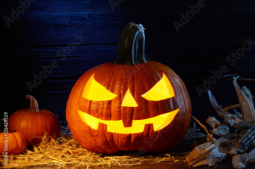 Carved pumpkin or so called jack-o-lantern in dark barn, Halloween holiday celebration concept photo