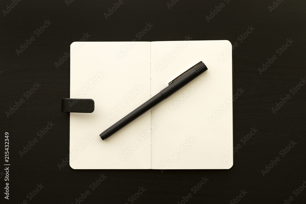 sketchbook with pen over black wooden table monochromatic flat lay composition sketchbook with pen over black wooden table monochromatic flat lay composition