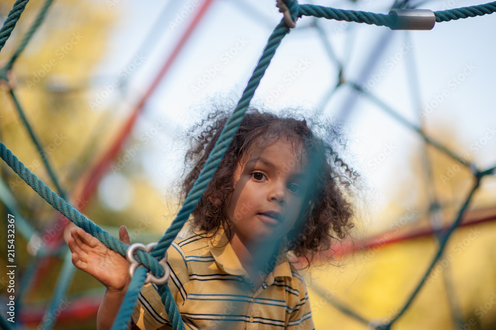 Child playing climbing net at playground Child playing climbing net at playground