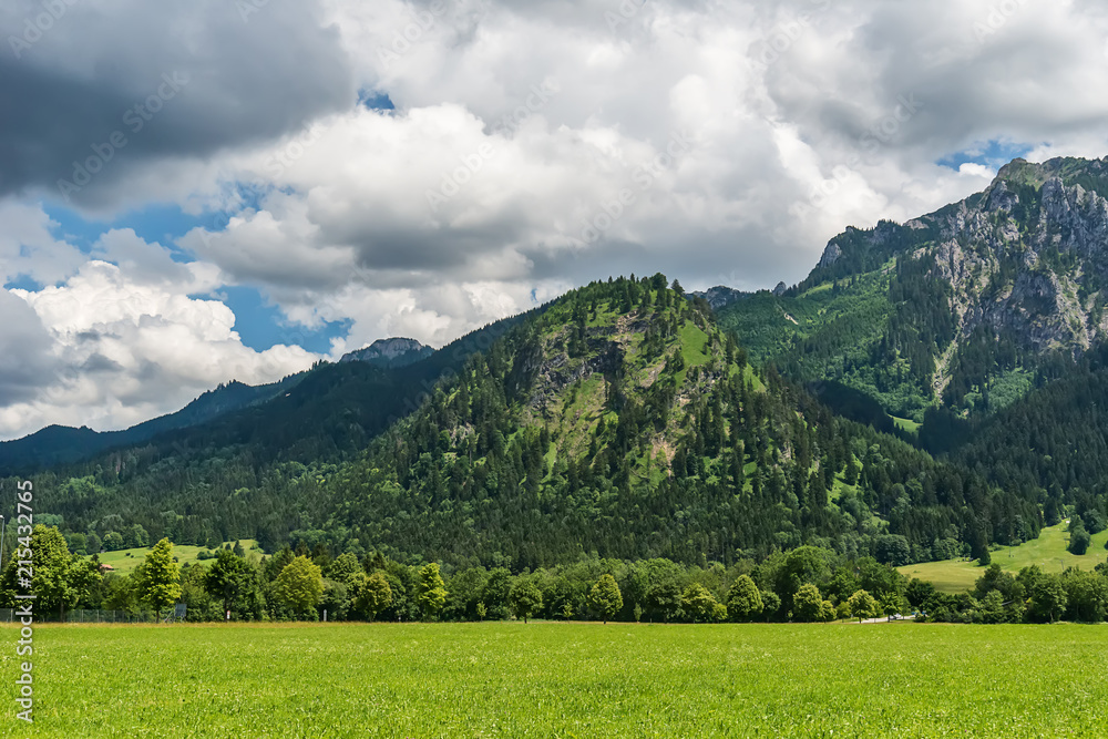 Fototapeta premium Idyllic landscape in the Alps with green meadows and clouds