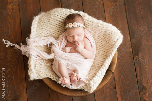 Newborn girl on a brown background. Photoshoot for the newborn. 7 days from birth. A portrait of a beautiful, seven day old, newborn baby girl