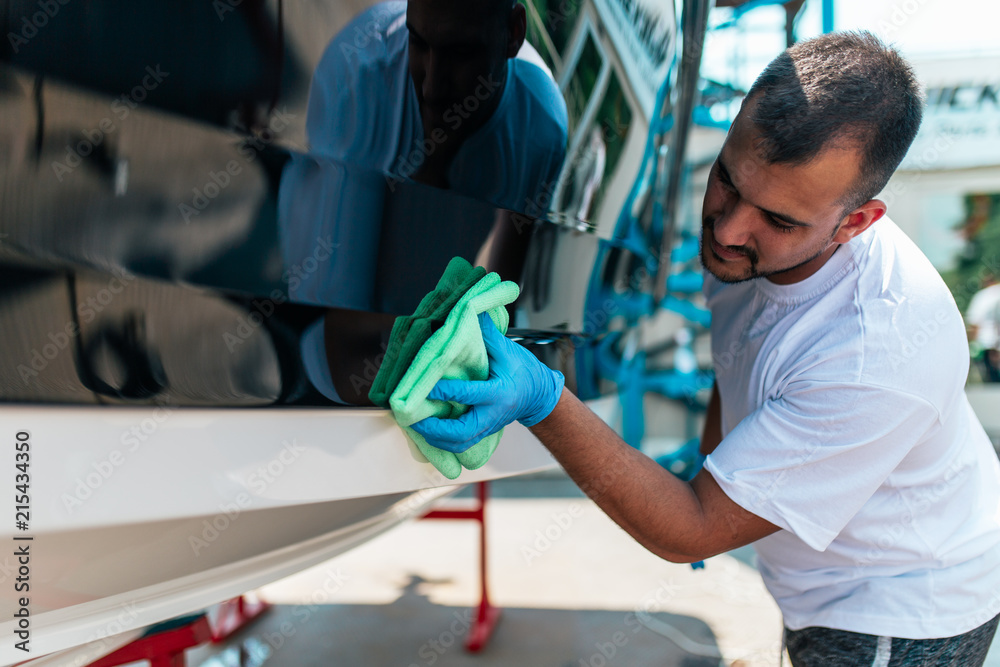 Fototapeta premium Boat maintenance - A man cleaning boat with cloth.