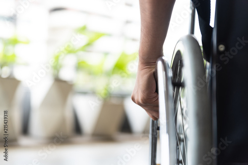 closeup disabled man hand on wheel of wheelchair photo