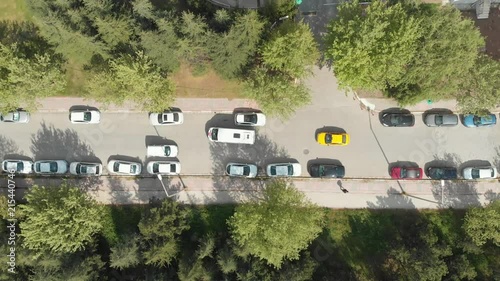 Drone looking down, flying sideways tracking van and taxi cab in a green suburban area photo