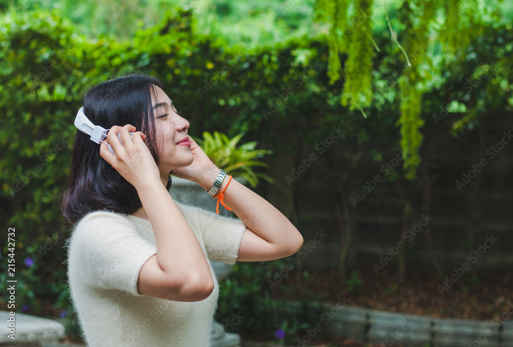 Naklejka premium Beautiful Asian girl listening to music in the garden.